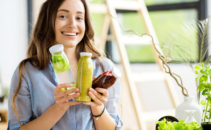 Frau hält mehrere Flaschen mit gesunden Säften: Weiterbildung Ernährungsberater